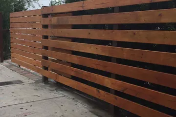 Horizontal stained wood fence along a sidewalk